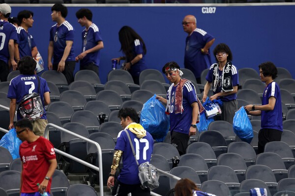  サッカー競技場でごみを片付ける日本ファンの姿。［写真 AP＝聯合ニュース］