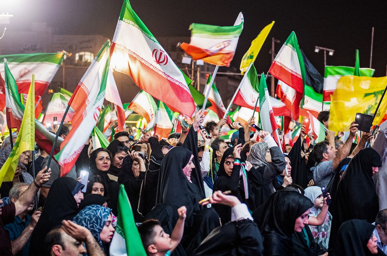   12日、イランの首都テヘランで、市民が米国との戦争終結に向けた政府の交渉を支持し、国旗を振っている。［UPI＝聯合ニュース］