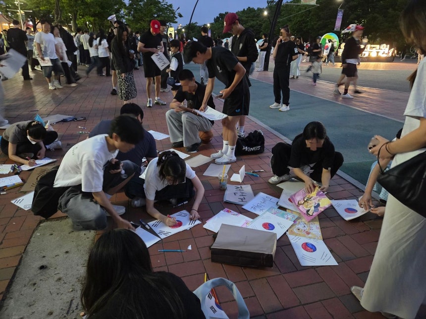 6日、ソウル松坡区（ソンパグ）オリンピック公園参政権デモに参加した青年が市民に配る太極旗を描いている。 ムン・ソヨン記者