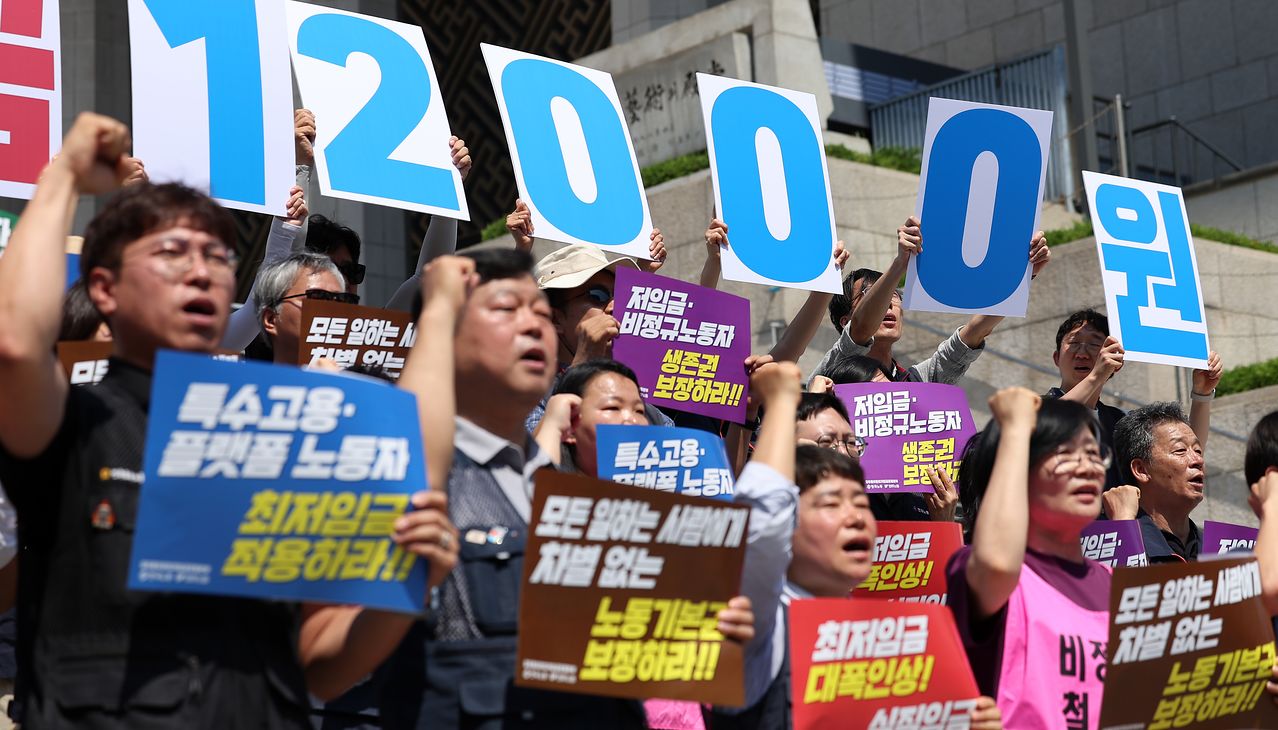 韓国労総と民主労総の関係者が15日に開かれた最低賃金労働界要求案発表記者会見でスローガンを叫んでいる。［写真 ニュース1］