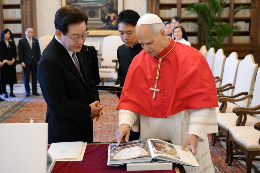 李在明（イ・ジェミョン）大統領が15日（現地時間）、バチカンの教皇宮で、ローマ教皇レオ14世から贈られた教皇謁見室の図録の説明を受けている。［写真 Vatican Media］
