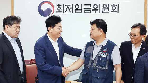 最低賃金委員会使用者委員運営委員であるリュ・ギジョン韓国経営者総協会専務（左）と労働者委員運営委員のリュ・ギソプ韓国労総事務総長が10日に開かれた全員会議で来年の最低賃金を1時間当たり1万320ウォンと17年ぶりに合意で決めた後握手している。［写真 聯合ニュース］