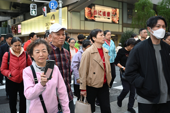 2025年11月17日、東京銀座のショッピング街で中国人団体観光客が道路を渡っている。［AFP＝聯合ニュース］
