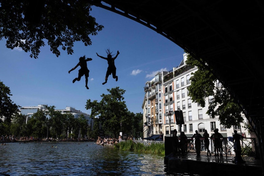22日、フランスのパリで猛暑の中で若者がサンマルタン運河に橋から飛び込んでいる。［写真 AFP＝聯合ニュース］