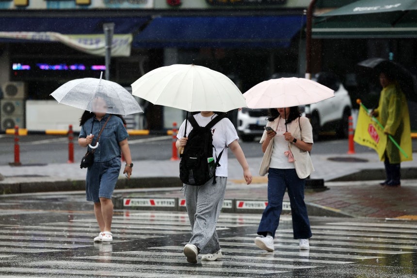 今年初めての梅雨空となった1日午前、光州市北区梧峙洞（クァンジュシ・プック・オチドン）の道路で、市民らが傘を差して移動している。［聯合ニュース］