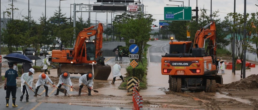 豪雨が降った9日、世宗市（セジョンシ）ハンビョル洞のBRT交差点付近では、工事現場から流出した土砂で道路が覆われ浸水したことを受けて作業員が復旧作業を行っている。聯合ニュース