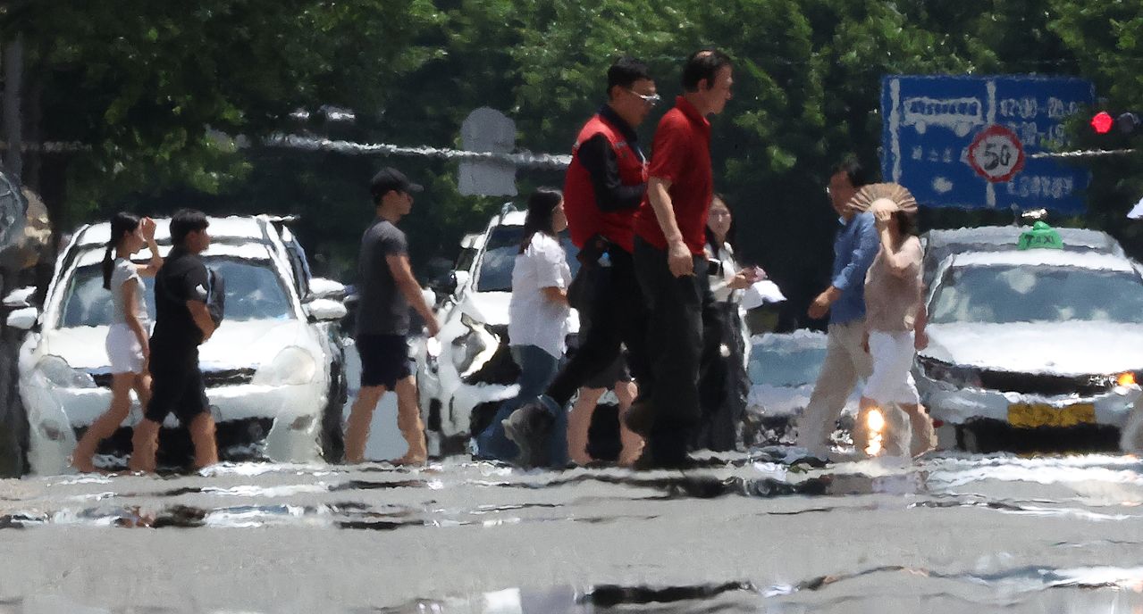 韓国・大邱（テグ）に猛暑警報が発令された11日、大邱市中区（チュング）の公平（コンピョン）交差点で、市民が地熱による陽炎が立ち上る道路を歩いている。［聯合ニュース］