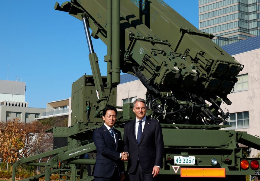 2025年12月7日、日本の小泉進次郎防衛相（左）とオーストラリアのマールズ国防相が東京の防衛省に配備されたパトリオット性能向上型（PAC－3）迎撃ミサイル部隊の前で握手している。［AP＝聯合ニュース］