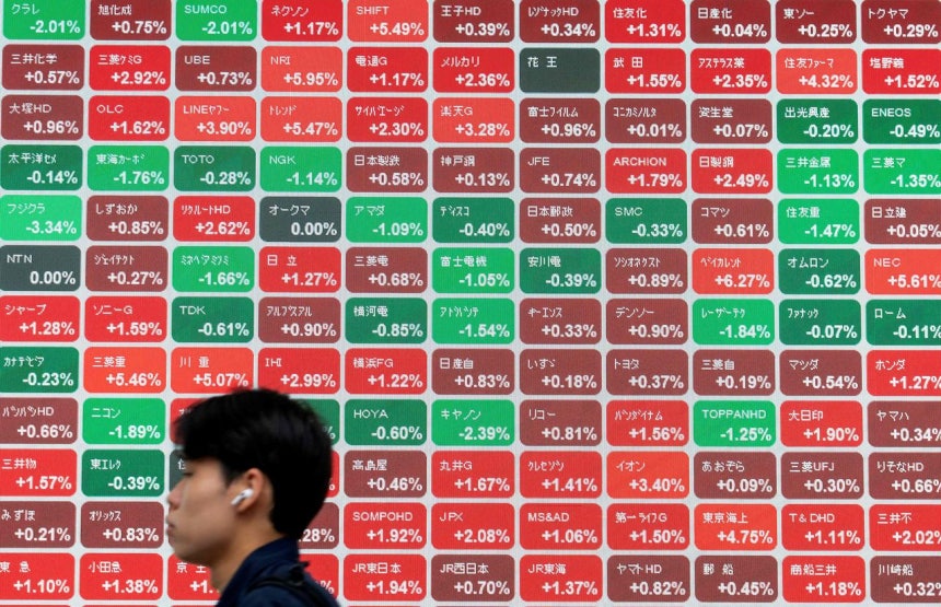 6月29日、東京証券取引所の日経平均株価が表示された電光掲示板の前を男性が通り過ぎている。AFP＝聯合ニュース