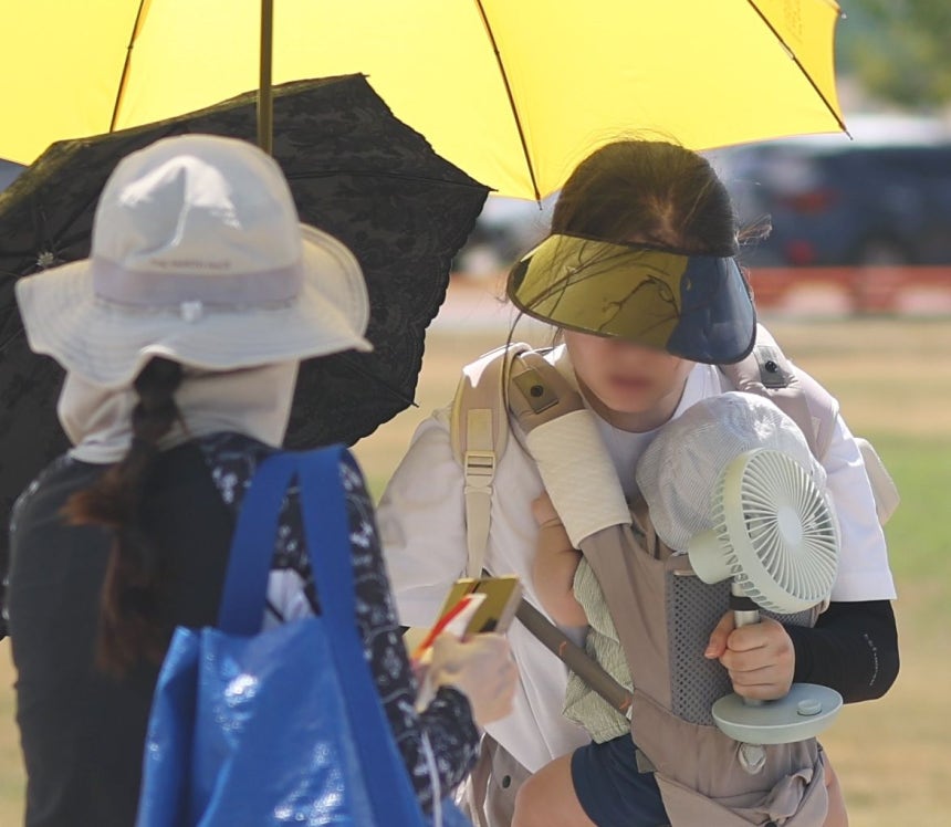 慶尚南道梁山（ヤンサン）地域の気温が41．4度まで上がった31日午後、梁山市勿禁邑の黄色公園で市民が傘と携帯扇風機を持って移動している。［聯合ニュース］