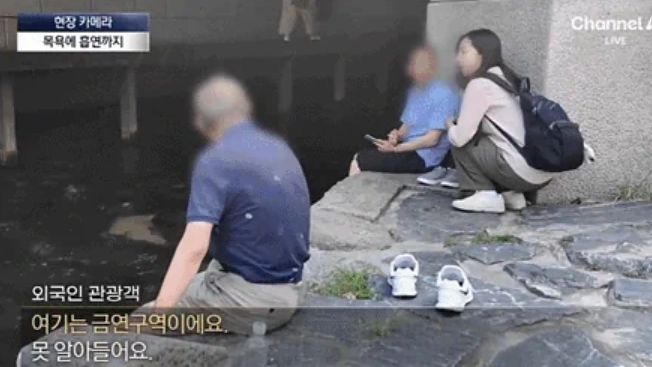   清渓川（チョンゲチョン）でたばこを吸う中国人観光客。［チャンネルA報道画面 キャプチャー］