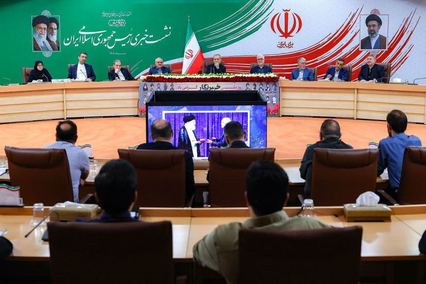 8日、記者会見をするイランのペゼシュキアン大統領（国旗の右隣） ［AFP＝聯合ニュース］