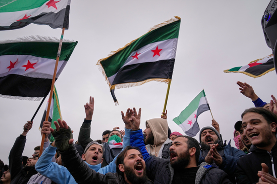 昨年12月、シリアのダマスカスで市民がバッシャール・アサド政権追放1周年を記念して国旗を振っている。［AP＝聯合ニュース］