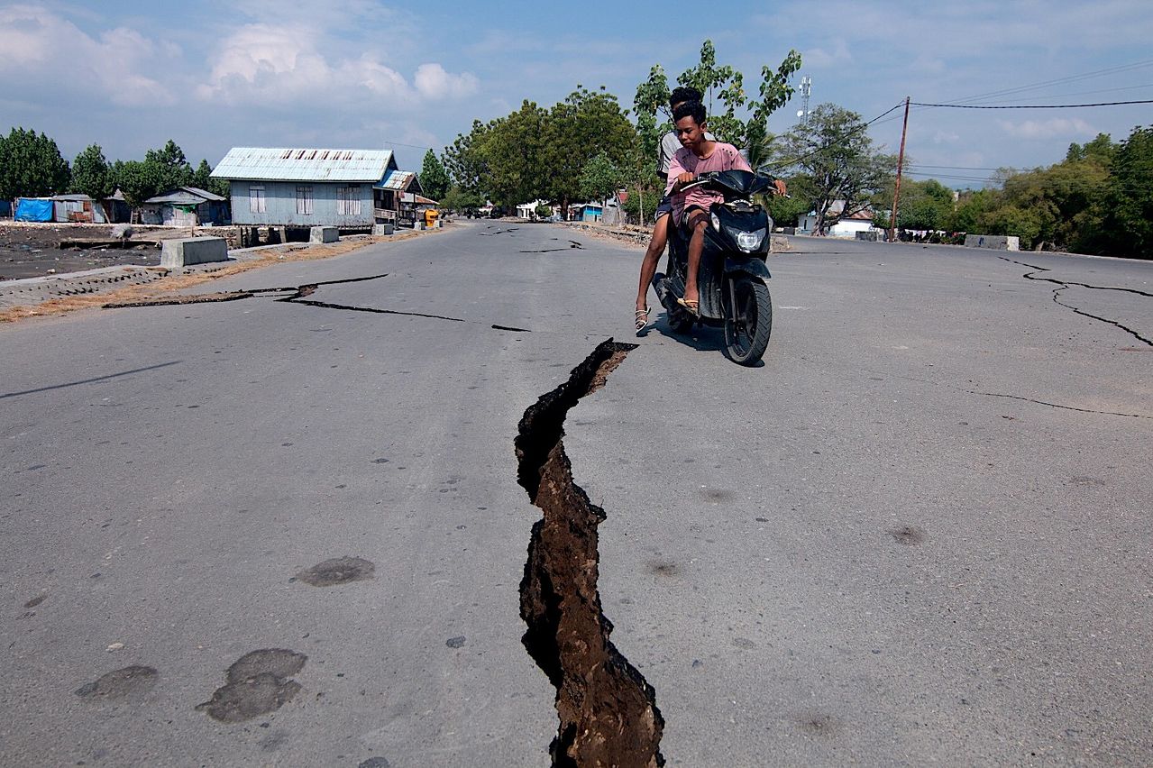 15日（現地時間）、インドネシア東ヌサトゥンガラ州ナゲケオのムバイで、マグニチュード（M）7．7の地震により亀裂が入った道路の近くをオートバイの運転手が通っている。EPA＝聯合ニュース