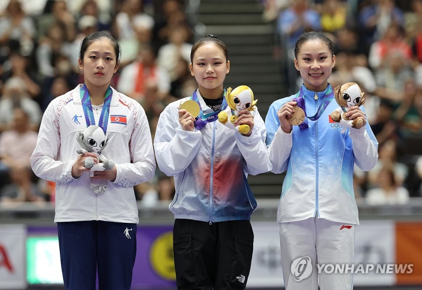 女子跳馬表彰式で明るく笑う韓国・中国選手と、それとは対照的な北朝鮮選手の無表情。［写真 聯合ニュース］