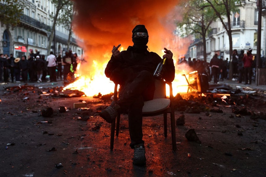 17日（現地時間）、フランス・パリで行われたデモで、黒い服を着てマスクを着用した参加者がバリケードの前の椅子に座り、中指を立てている。［ロイター＝聯合ニュース］